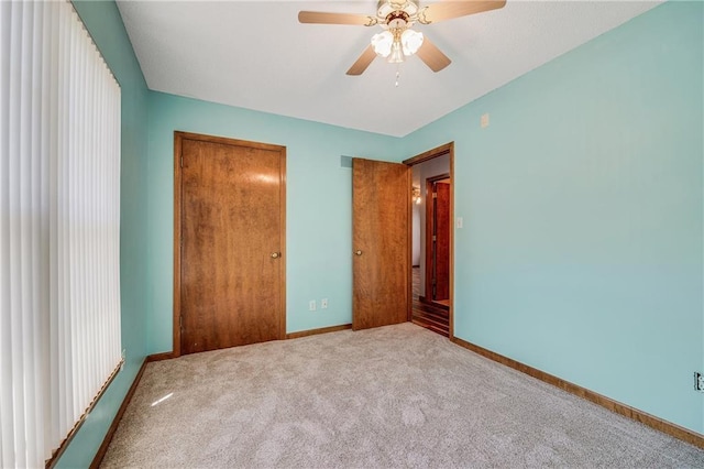 unfurnished bedroom with carpet floors, a closet, baseboards, and a ceiling fan