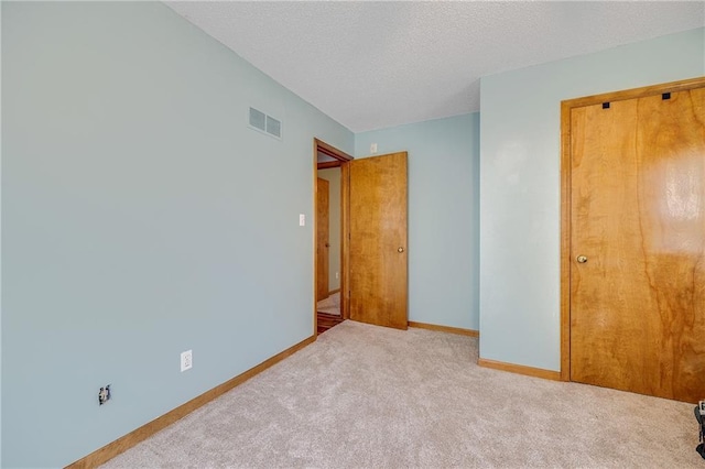 unfurnished bedroom with carpet flooring, baseboards, and a textured ceiling