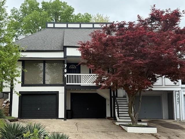 view of front of home with a garage, driveway, stairs, and roof with shingles