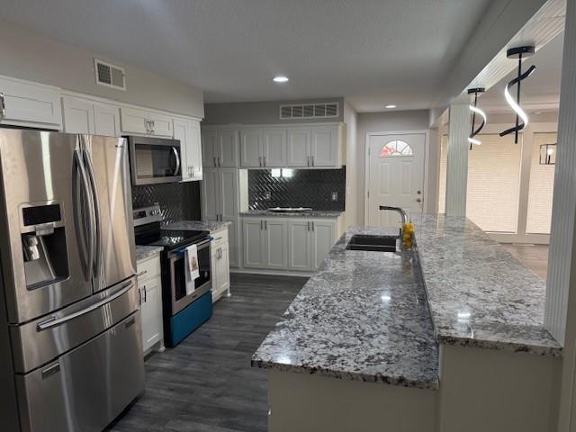 kitchen with a sink, visible vents, white cabinetry, and stainless steel appliances