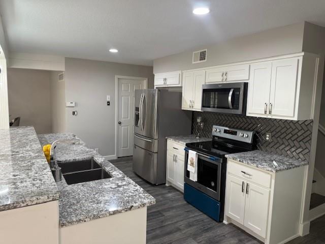 kitchen with appliances with stainless steel finishes, dark wood-style flooring, visible vents, and a sink