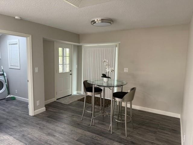 dining area featuring baseboards, washer / dryer, a textured ceiling, and dark wood-style floors