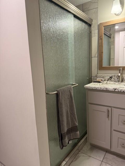 bathroom featuring marble finish floor, vanity, and a shower with door