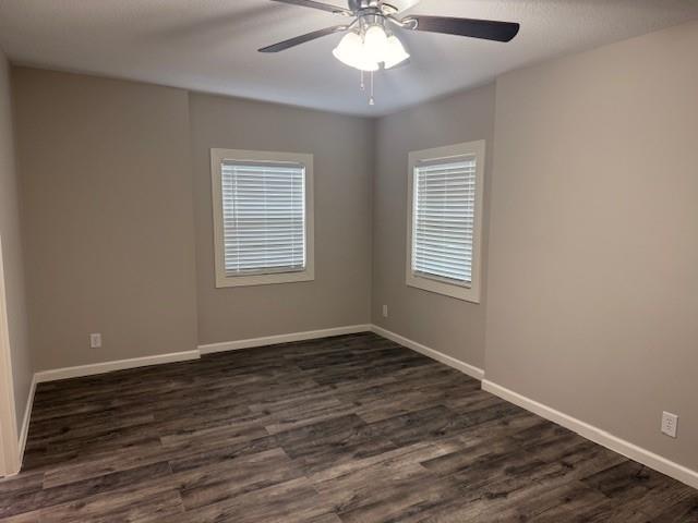 spare room with a ceiling fan, dark wood-style flooring, and baseboards