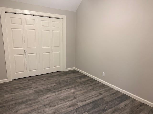 unfurnished bedroom featuring dark wood-type flooring, a closet, and baseboards