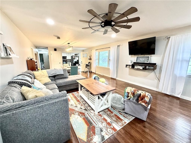 living room featuring baseboards, ceiling fan, and wood finished floors