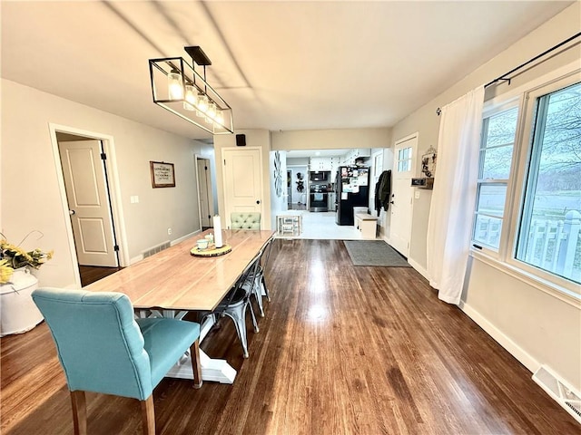 dining space with baseboards, visible vents, and wood finished floors