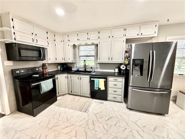 kitchen featuring dark countertops, a sink, black appliances, marble finish floor, and white cabinetry