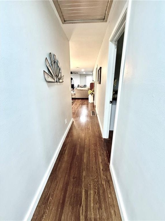 hallway with baseboards, dark wood finished floors, and visible vents