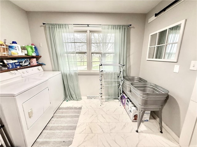 clothes washing area featuring baseboards, laundry area, washing machine and dryer, and marble finish floor