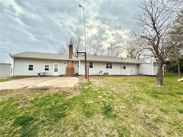 rear view of house with a patio, a yard, a chimney, and cooling unit