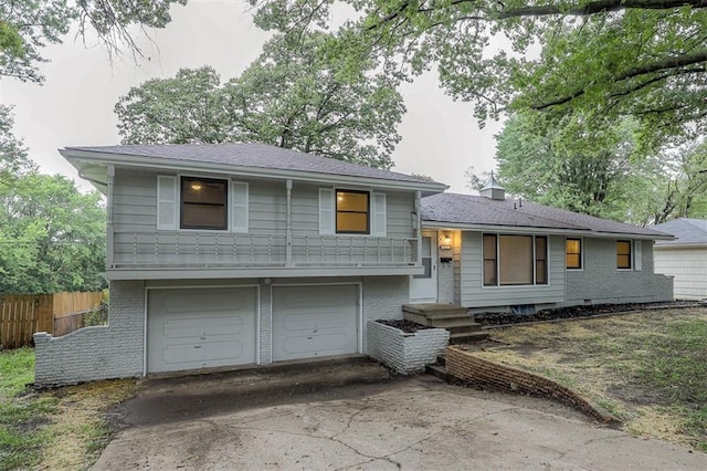 split level home featuring brick siding, driveway, an attached garage, and fence