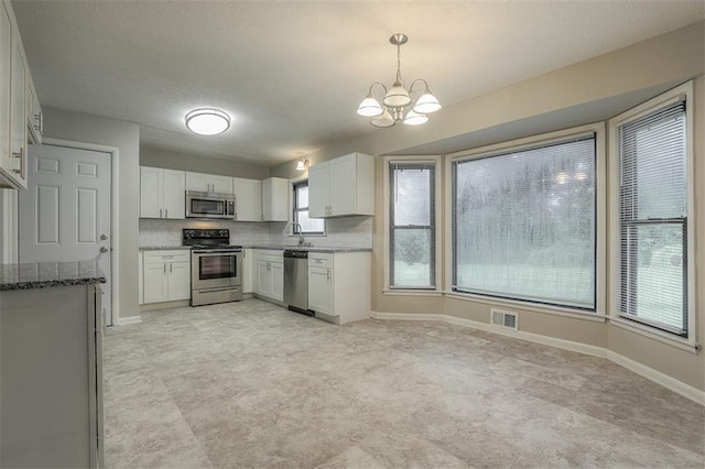 kitchen featuring dark stone countertops, a notable chandelier, visible vents, white cabinetry, and appliances with stainless steel finishes