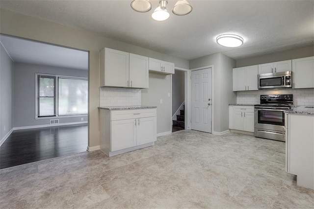 kitchen featuring baseboards, white cabinetry, stainless steel appliances, and decorative backsplash