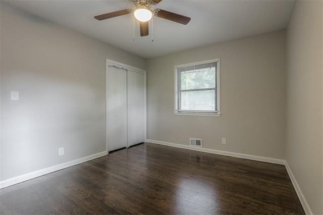 unfurnished bedroom with wood finished floors, a closet, visible vents, and baseboards