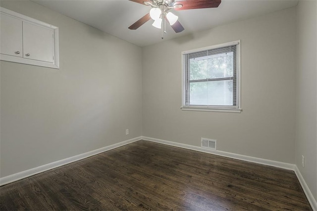 spare room with dark wood-style floors, visible vents, ceiling fan, and baseboards