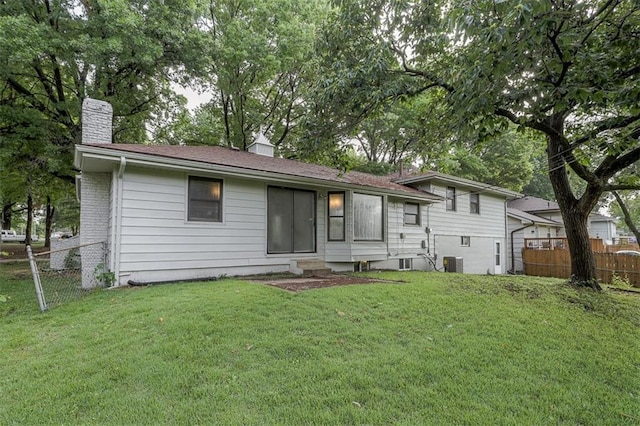 back of property featuring fence, a yard, central AC, and a chimney