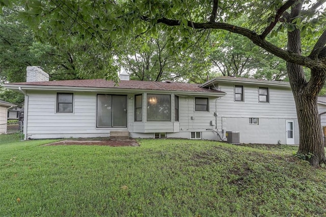 view of front facade with a chimney, fence, entry steps, central AC unit, and a front yard