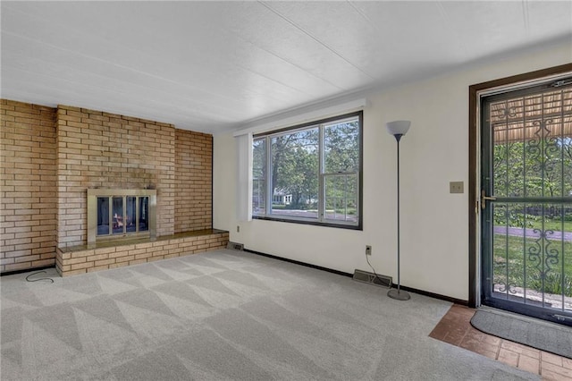 unfurnished living room featuring baseboards, carpet flooring, a brick fireplace, and visible vents