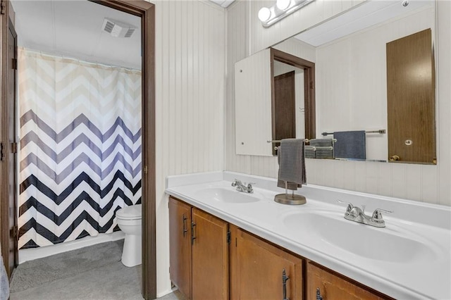 bathroom with a sink, toilet, double vanity, and visible vents