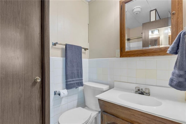 bathroom with vanity, toilet, and tile walls