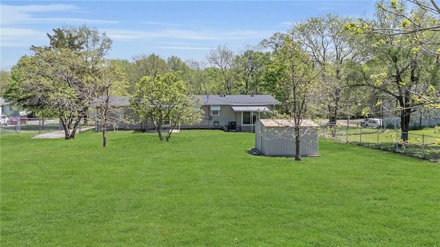 view of yard featuring an outbuilding, fence, and a storage shed