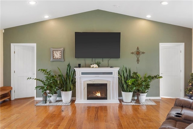living area featuring wood finished floors, baseboards, lofted ceiling, and a fireplace