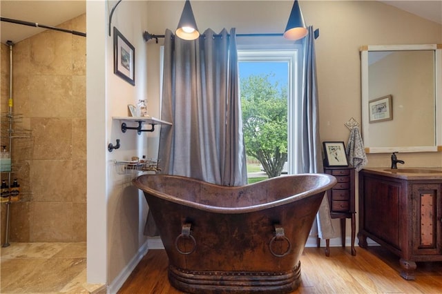 bathroom featuring a freestanding tub, a tile shower, and wood finished floors