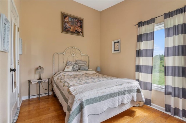 bedroom featuring baseboards, wood finished floors, and multiple windows