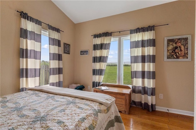 bedroom featuring baseboards, lofted ceiling, and wood finished floors