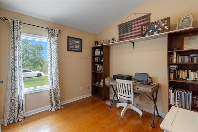 home office featuring baseboards, wood finished floors, and vaulted ceiling