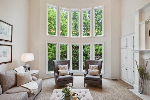 living room featuring a high ceiling, light colored carpet, and baseboards