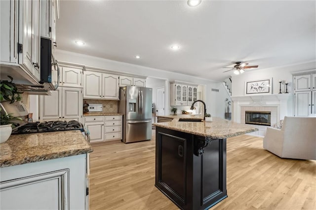 kitchen with stainless steel fridge with ice dispenser, ornamental molding, a ceiling fan, a sink, and a fireplace
