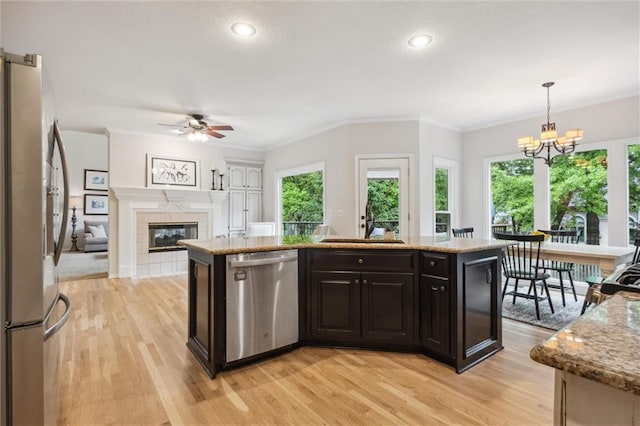 kitchen featuring stainless steel appliances, light wood-type flooring, ceiling fan, a chandelier, and light stone countertops