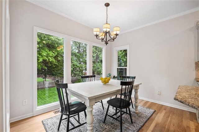 dining space with a chandelier, light wood-style floors, baseboards, and crown molding