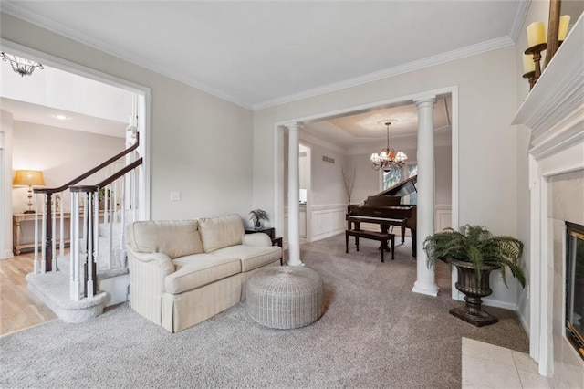 living room featuring crown molding, decorative columns, a chandelier, stairs, and light carpet
