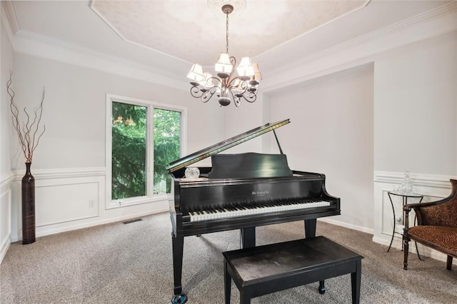 living area with carpet flooring, a chandelier, a tray ceiling, ornamental molding, and a wainscoted wall