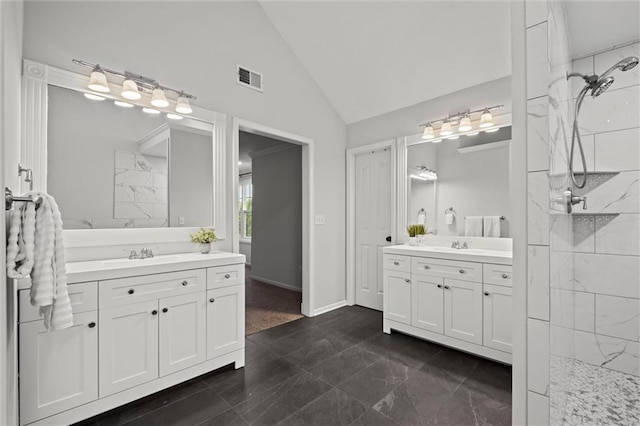 bathroom featuring walk in shower, two vanities, baseboards, and high vaulted ceiling