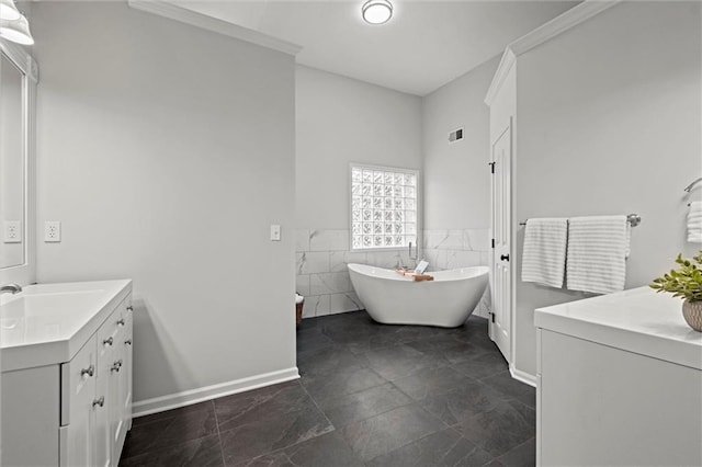 full bath featuring vanity, baseboards, tile walls, a soaking tub, and wainscoting