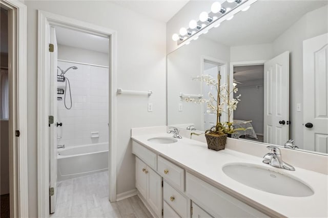 bathroom featuring double vanity, baseboards, and washtub / shower combination