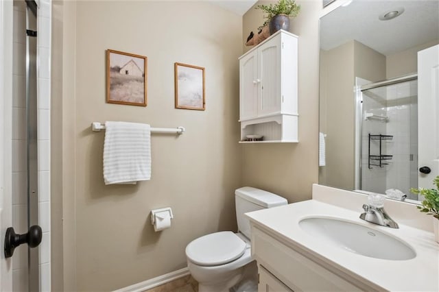 bathroom with a shower stall, toilet, vanity, and baseboards
