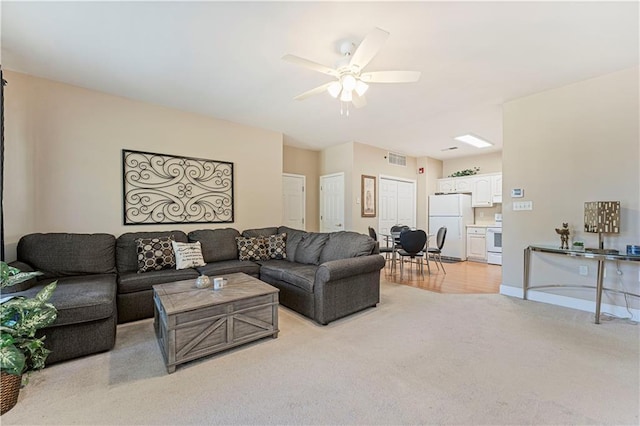 living area featuring a ceiling fan, visible vents, light colored carpet, and baseboards
