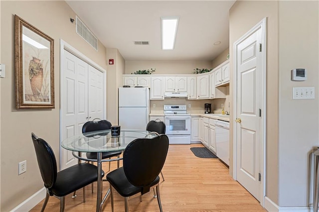 kitchen with light wood-type flooring, visible vents, white appliances, and white cabinets
