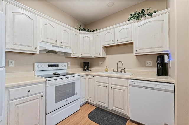 kitchen with white appliances, light wood-style flooring, under cabinet range hood, light countertops, and a sink