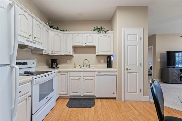 kitchen with white cabinets, a sink, under cabinet range hood, light wood finished floors, and white appliances