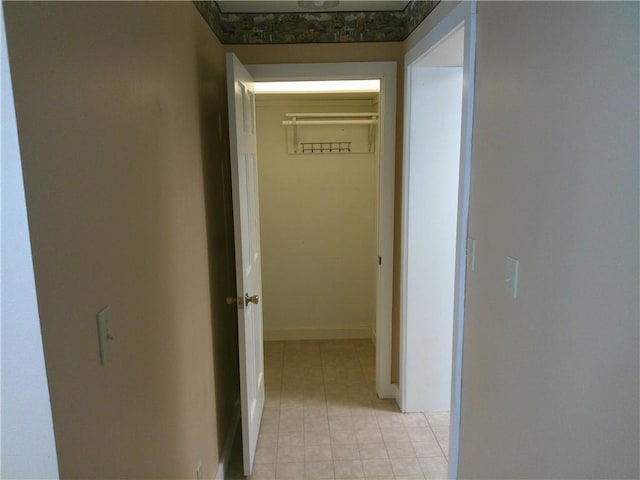 corridor with baseboards and light tile patterned floors
