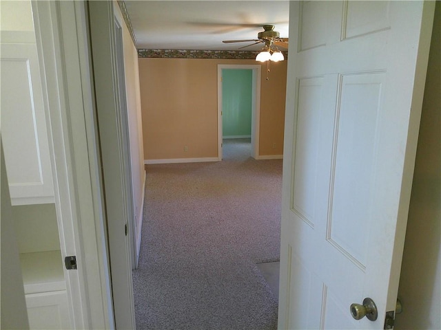hall featuring baseboards and light colored carpet