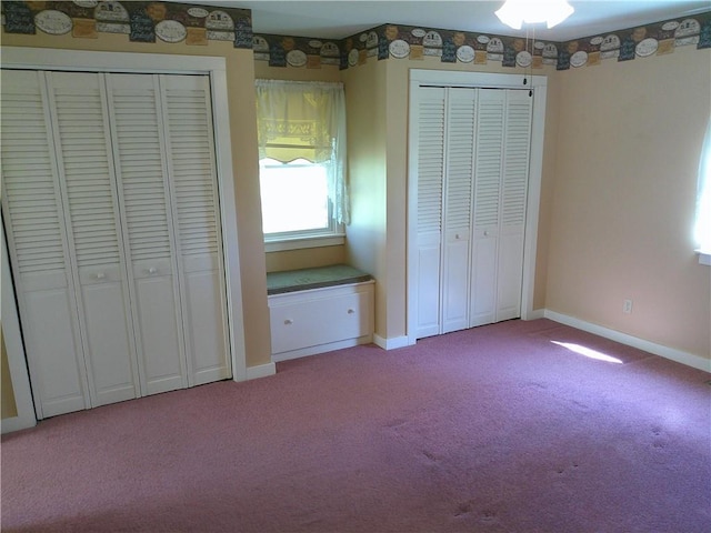 unfurnished bedroom featuring multiple closets, baseboards, and light colored carpet