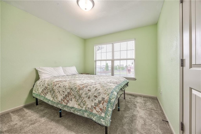 carpeted bedroom with baseboards and a textured wall