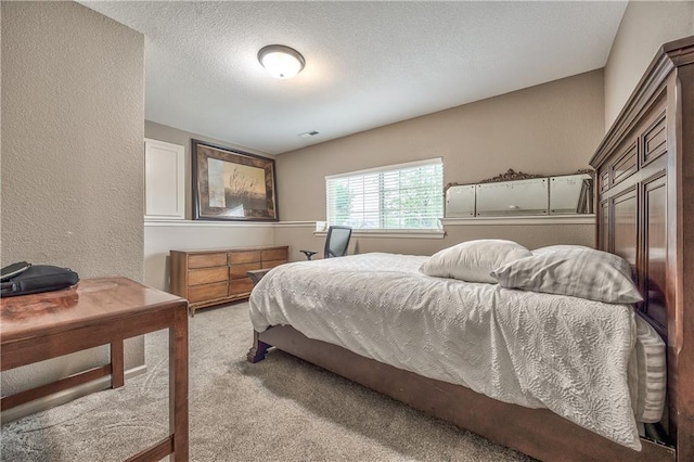 carpeted bedroom with a textured wall and a textured ceiling